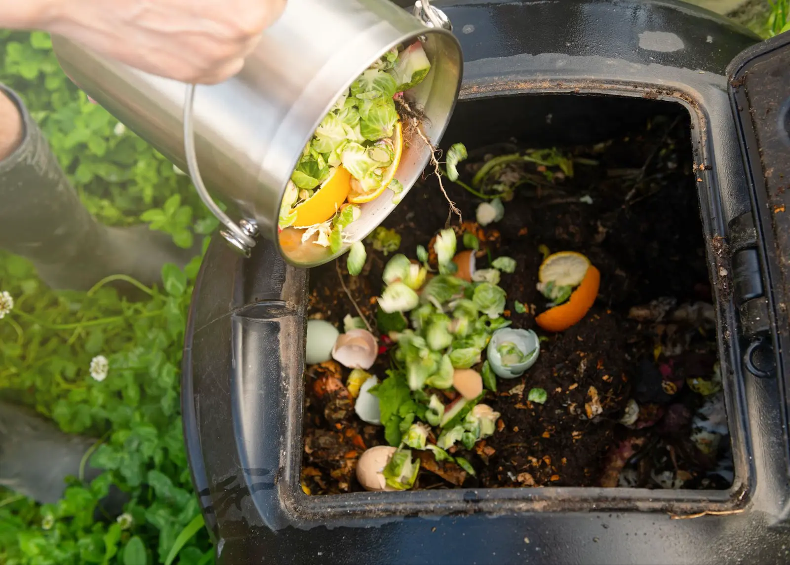 A grower adding vegetables into their compost bin.