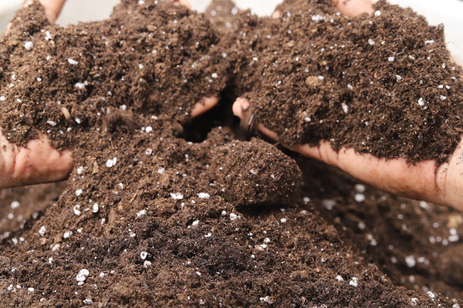 Hands mixing light airy soil